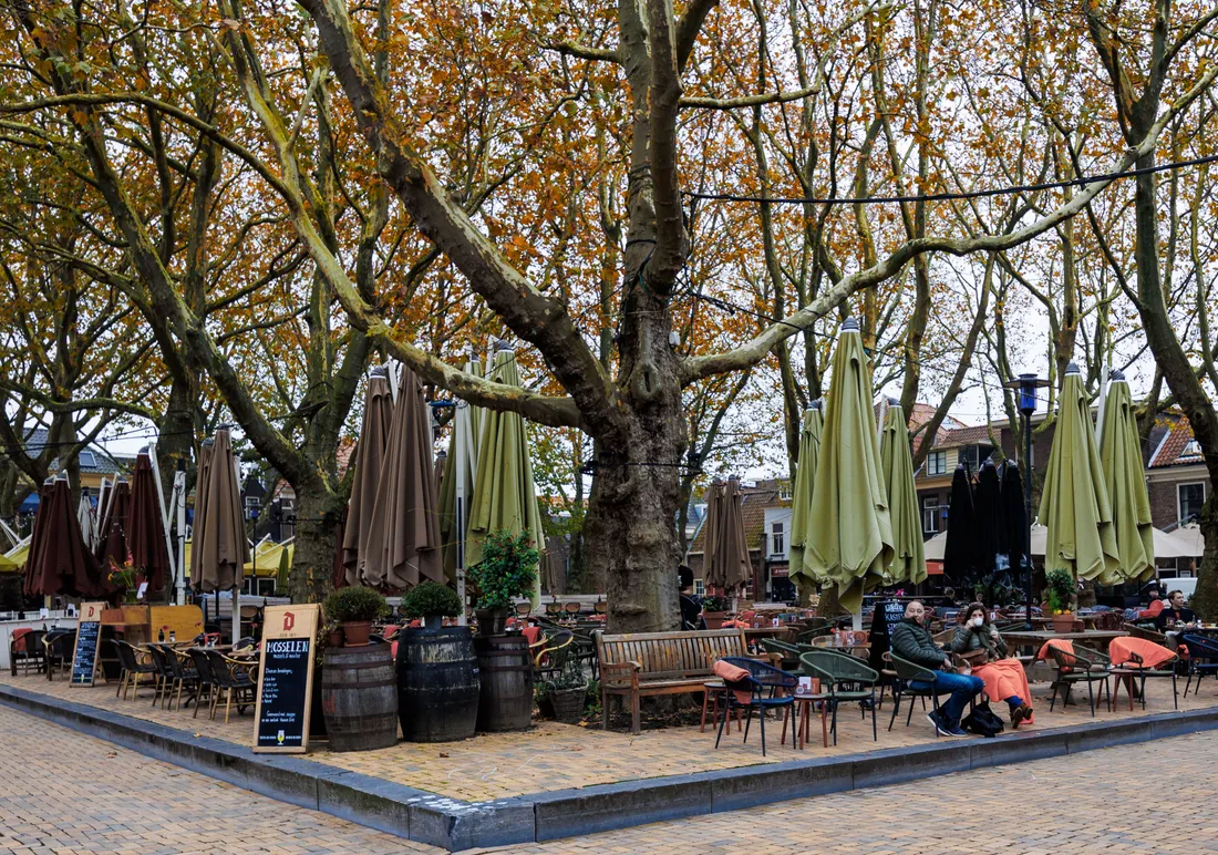 Belebter Neuköllner Stadtplatz mit Cafés und Menschen im Kiez